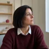 Portrait de Judith Chassaing, cheveux noirs au carré, pull bordeaux sur une chemise blanche, dans une pièce claire
